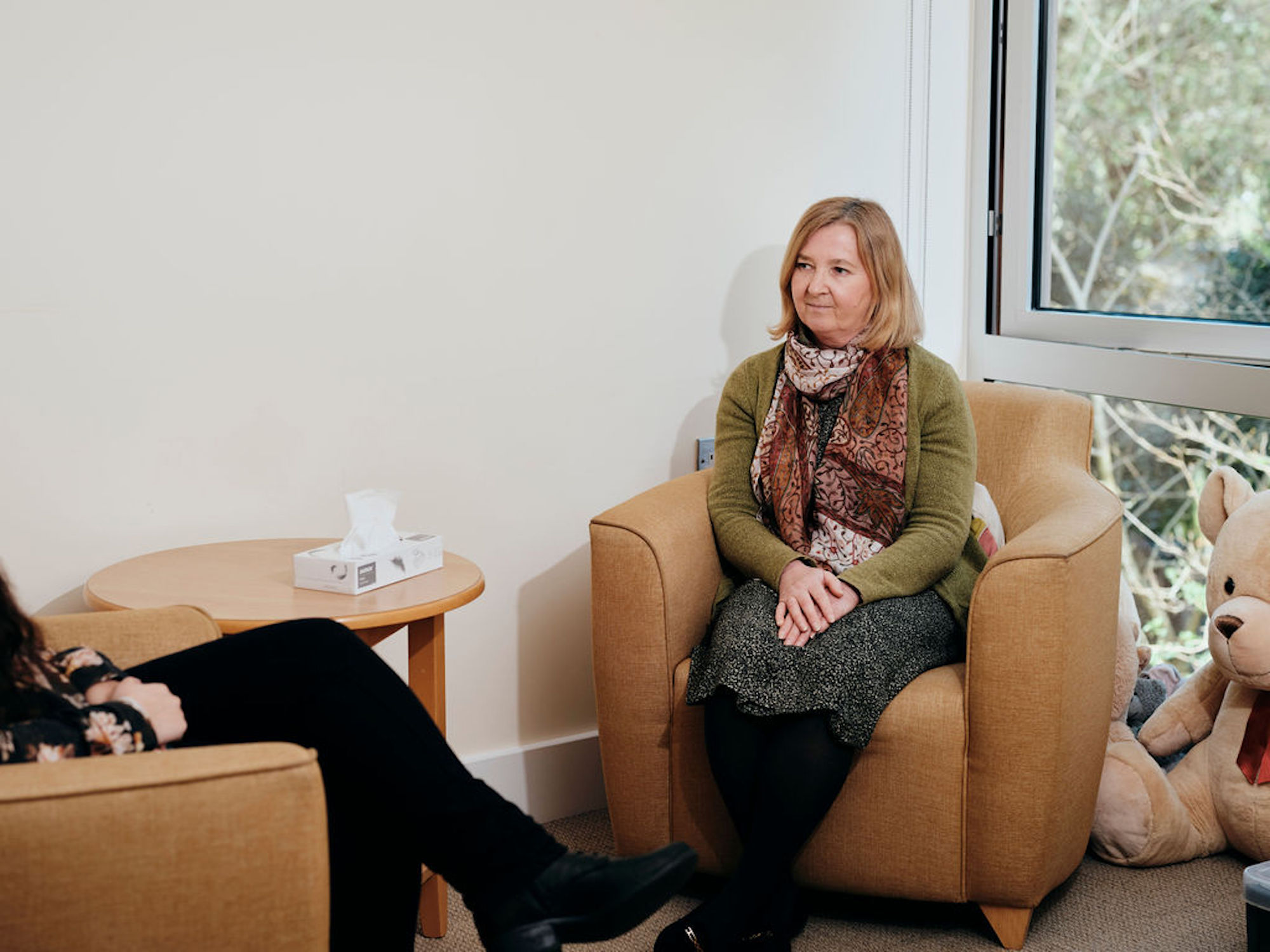Image of bereavement counsellor talking to patient, box of tissues on table 