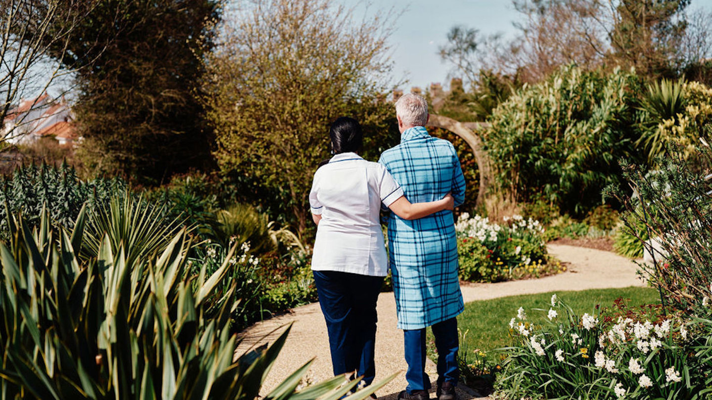 Image of nurse and patient walking in gardens at Jersey Hospice Care