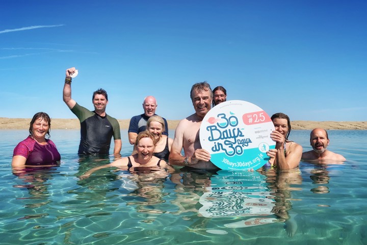 Image of swimmers in the sea with 30 Bays in 30 Days sign