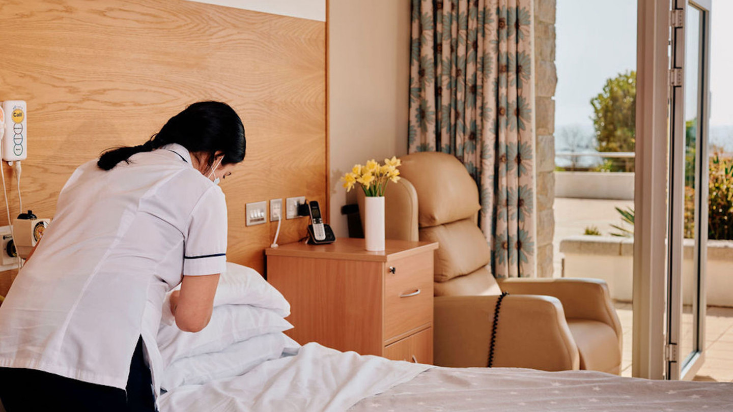 Image of nurse making a bed in patient room